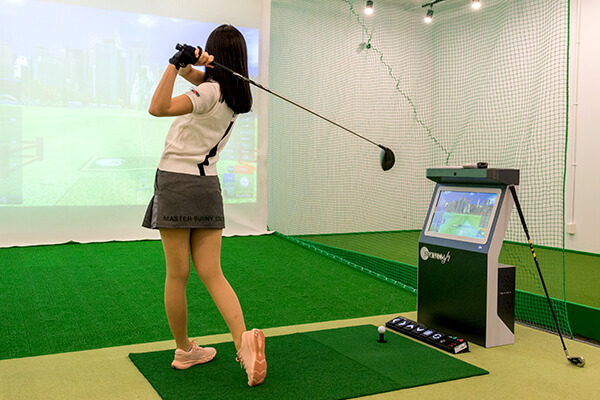 シミュレーションゴルフをする女性の写真